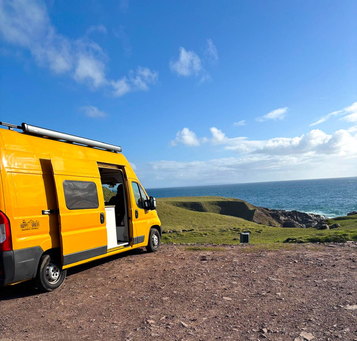 Gele camper met uitzicht op de Schotse kust tijdens een offgrid camperreis door Schotland.