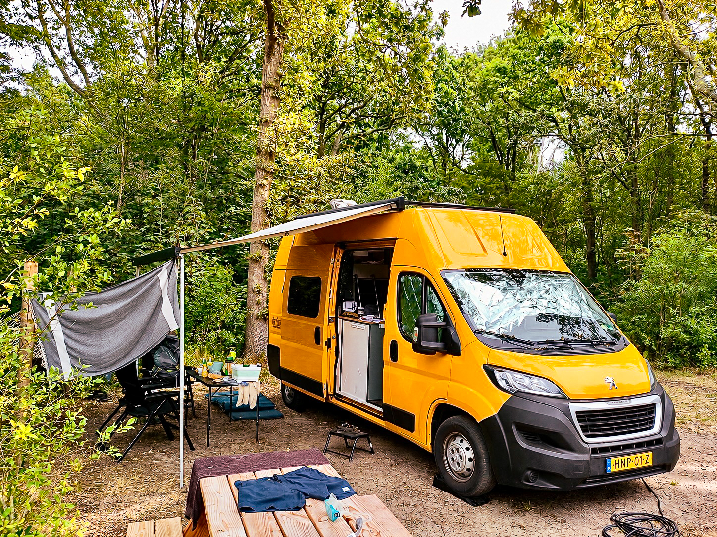 Oranje camperbus op een groene camping in de natuur